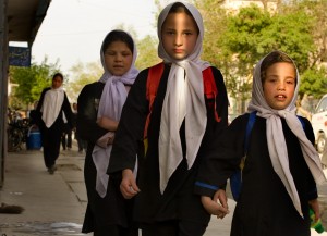 Girls in white head scarves make their way home from school after class in Kabul.